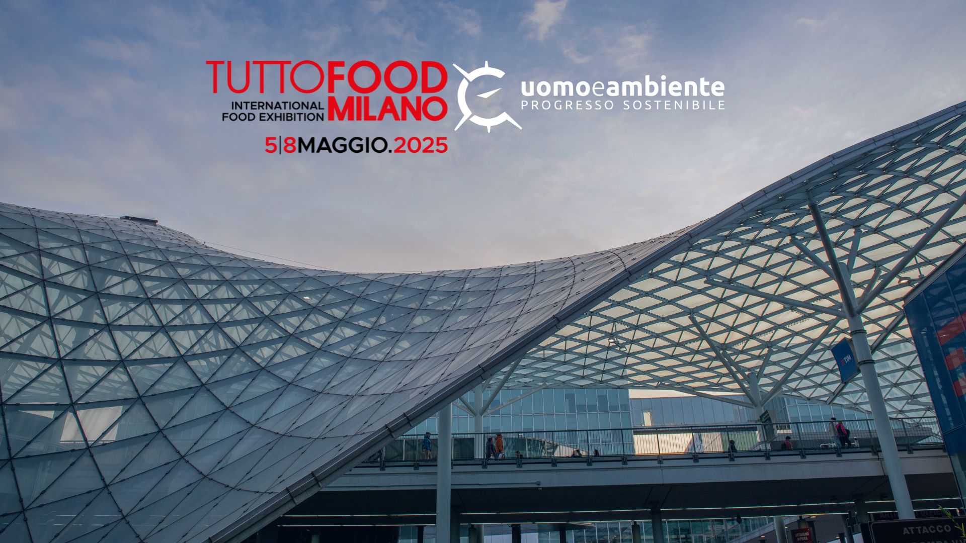 Veduta della moderna copertura in vetro e acciaio del polo fieristico di Fiera Milano Rho, con il cielo al tramonto sullo sfondo. In alto, i loghi della fiera internazionale dell’alimentazione TUTTOFOOD Milano 2025 e del partner uomoeambiente, con la data dell’evento (5-8 maggio 2025) ben evidenziata. L’immagine comunica innovazione, sostenibilità e centralità del design architettonico nell’accoglienza di eventi internazionali.